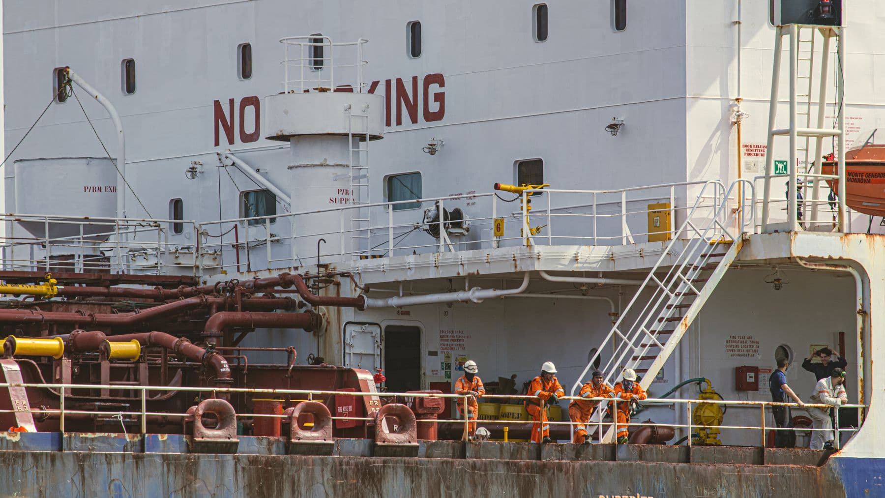 Crew members in safety gear on an industrial ship docked at Tampico Harbor, Mexico, engaging in maritime activities.