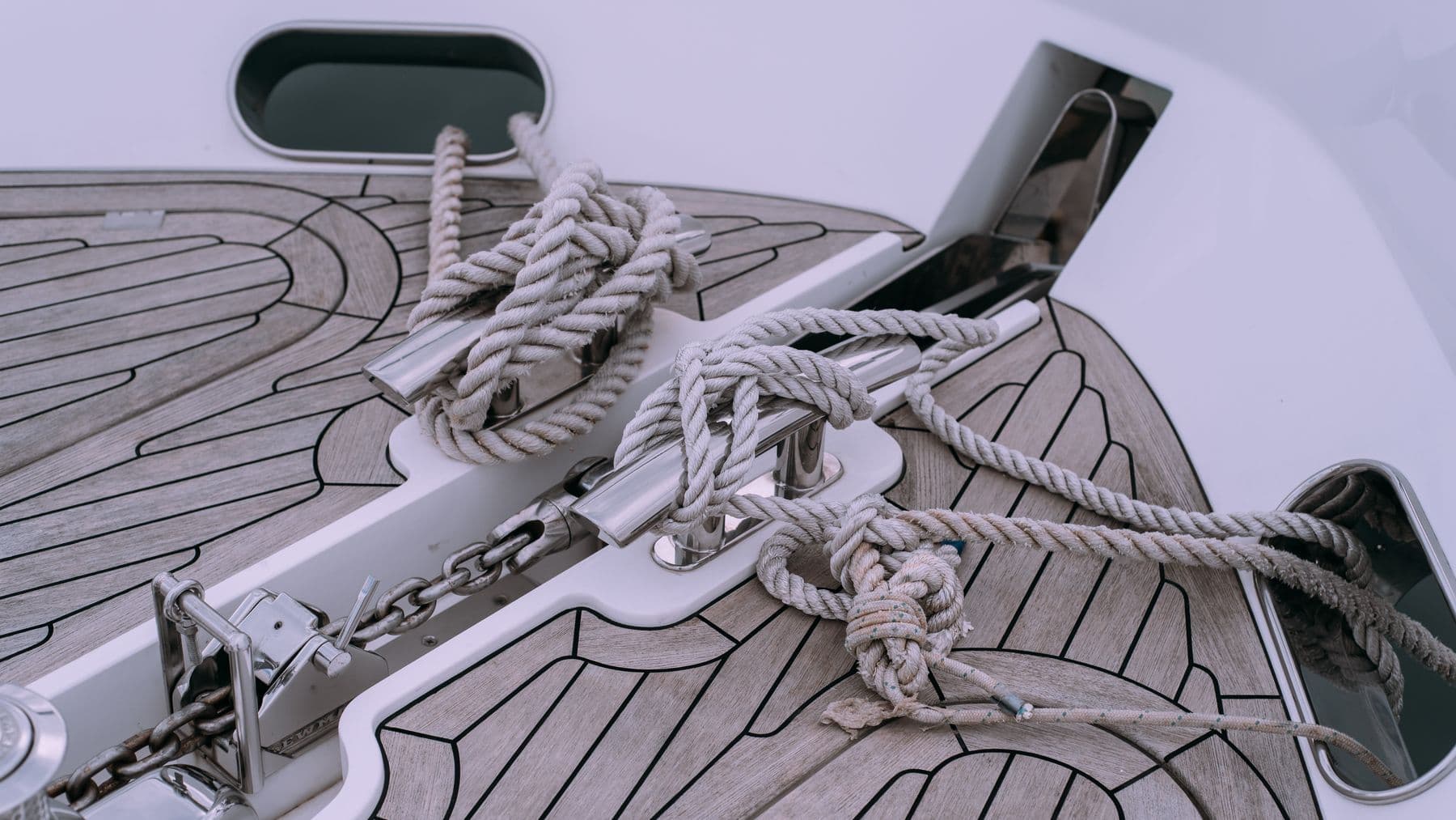 Detailed view of knotted ropes and chains on a boat deck, showcasing nautical materials.