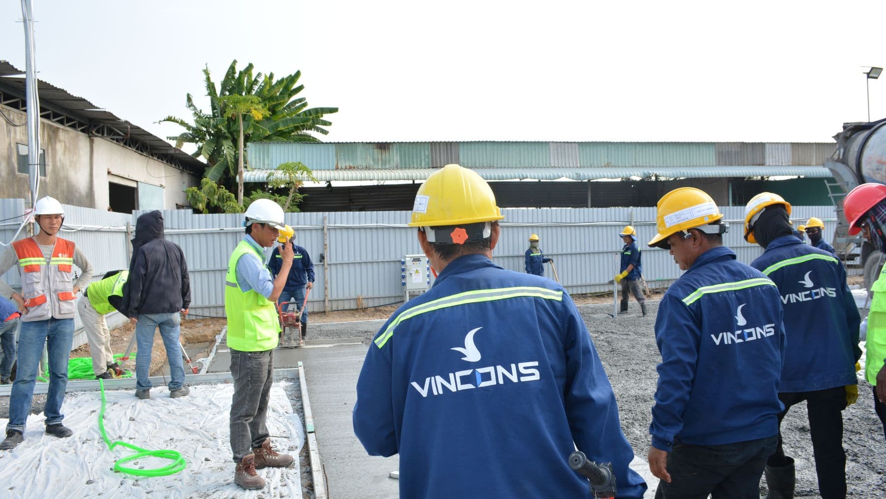 Group of construction workers wearing hard hats assessing a site outdoors.